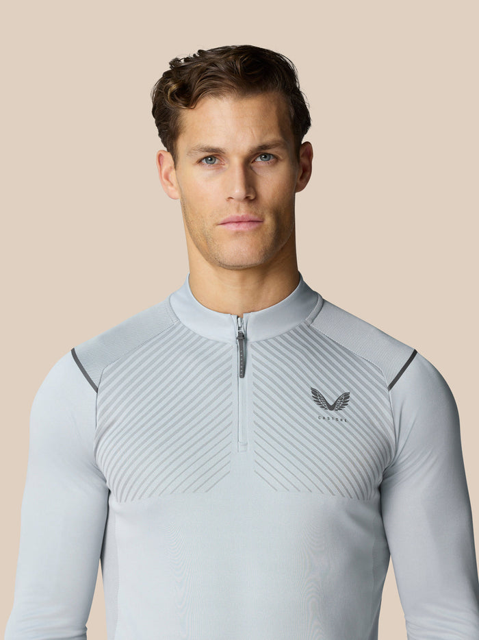 Male model wearing light grey Pinnacle LVS 1/4 zip top with diagonal chest stripes and stand collar