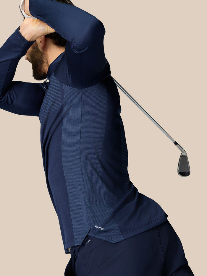 Side view of a man in navy LVS 1/4 Zip Top highlighting knit vent panels and curved hems for golf.
