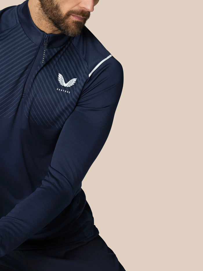 Male model wearing navy Pinnacle LVS 1/4 zip golf top with diagonal stripes and Castore logo