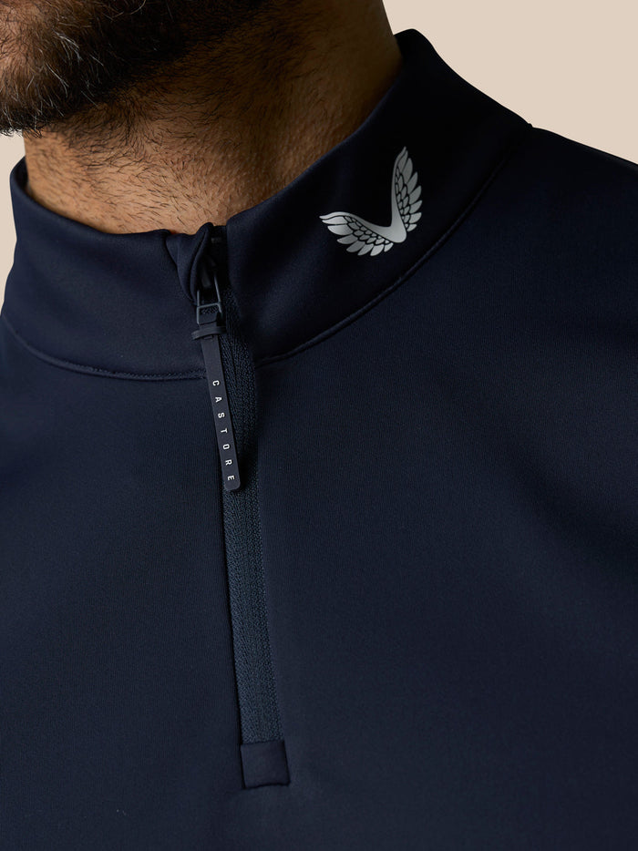 Close-up of navy Club 1/2 Zip Gilet collar with half zipper and Castore wing logo at the neck.