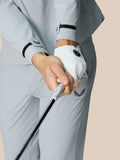 Close-up of the jacket cuff in mid grey with Castore branding while gripping a golf club.