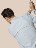Back view of a man wearing a light grey Castore Golf Pinnacle LVS woven jacket, with venting mesh panels and CASTORE on the collar
