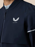Close-up of navy jacket chest with Castore logo and perforated sleeve detail