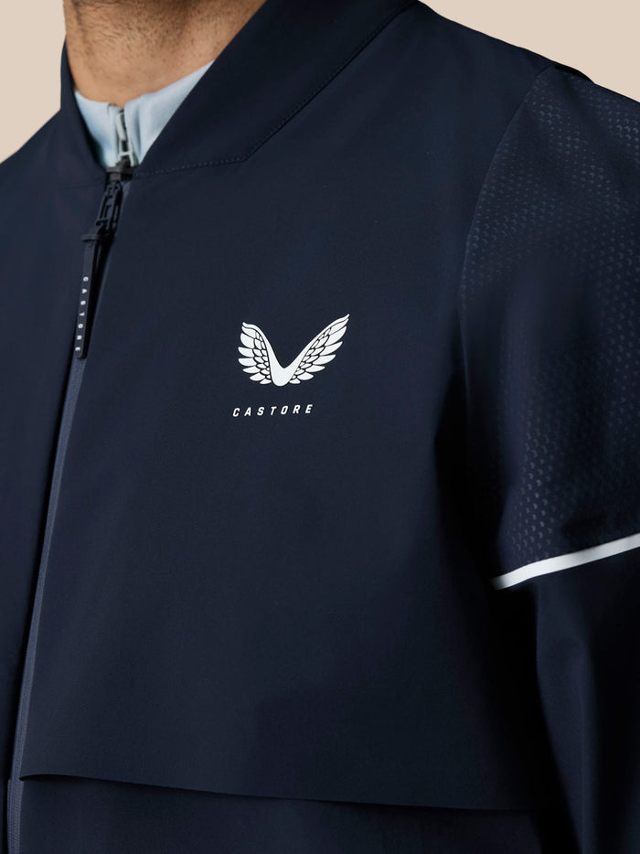 Close-up of navy jacket chest with Castore logo and perforated sleeve detail