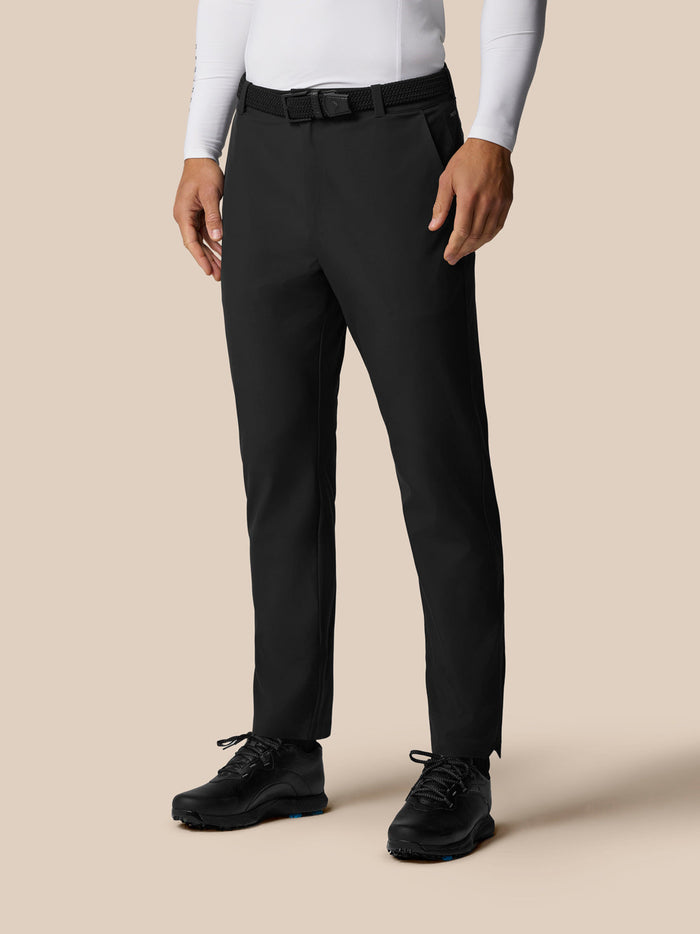 Golf Pinnacle Winter Trousers in black worn with a belt and hiking shoes, back pocket with Castore branding