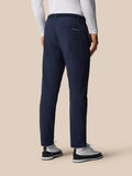 Back view of navy golf winterised trousers with belt and Castore branding on the back pocket with white sneakers