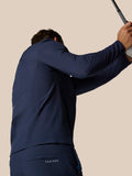 Back view of a golfer in navy Castore winter attire with raised arms and branding on the back pocket