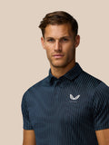 Close up of a man wearing midnight navy Pinnacle Glow Polo featuring all over striped knit and Castore logo.