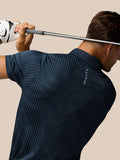 Golfer wearing GOLF PINNACLE GLOW POLO in midnight navy with stripe knit and Castore logo on chest holding a golf club behind his neck.