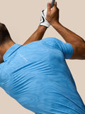 Back view of golfer in blue Glow Printed Polo showing striped fabric and Castore branding