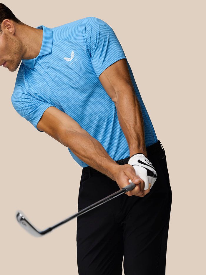 Golfer in blue Glow Printed Polo mid swing with striped knit fabric and left chest Castore logo