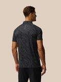Back view of a man wearing gunmetal gray glow printed golf polo with subtle wavy pattern and Castore branding along the upper back