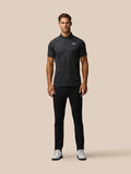 Male model wearing gunmetal gray glow printed golf polo with subtle pattern and Castore logo on chest.