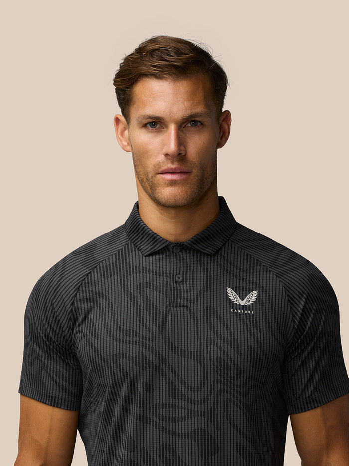 Close up front view of a man wearing a charcoal golf polo with a subtle striped pattern and Castore logo on the left chest
