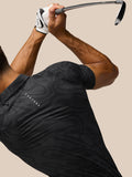Side view of golfer in glow printed polo with tonal stripes swinging a club; Castore logo on back.