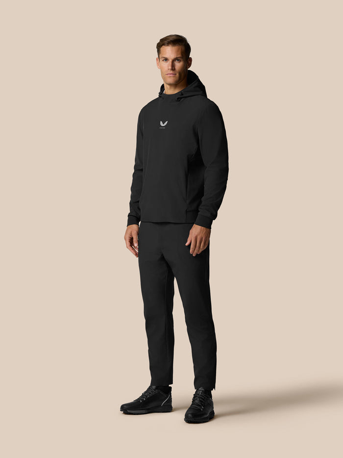 Front view of a man in a black Castore Golf Pinnacle Performance Hoodie featuring a small chest logo.