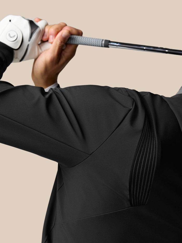 Close-up of the shoulder area of the black Golf Pinnacle Performance Hoodie showing fabric texture and ribbed panels