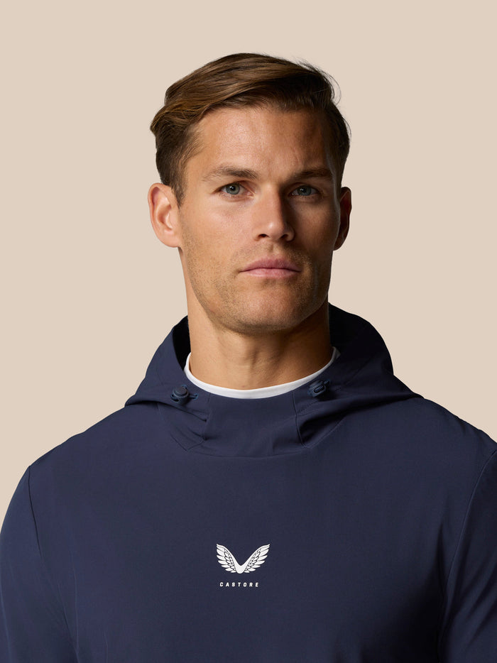 Male model wearing midnight navy Castore golf performance hoodie with center chest logo.