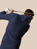 Back view of golfer in midnight navy Castore hoodie mid swing with ProTek badge.