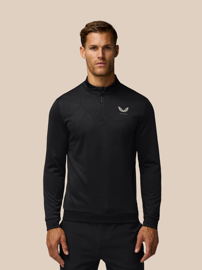 Man wearing black Golf Club Classic quarter zip top with all over print and chest Castore logo.