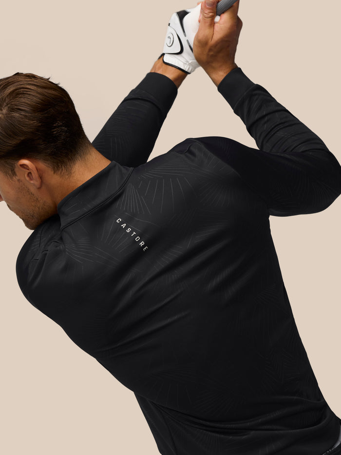 Male golfer in a black Golf Club Classic quarter-zip top with all-over print; Castore branding on back and left chest.
