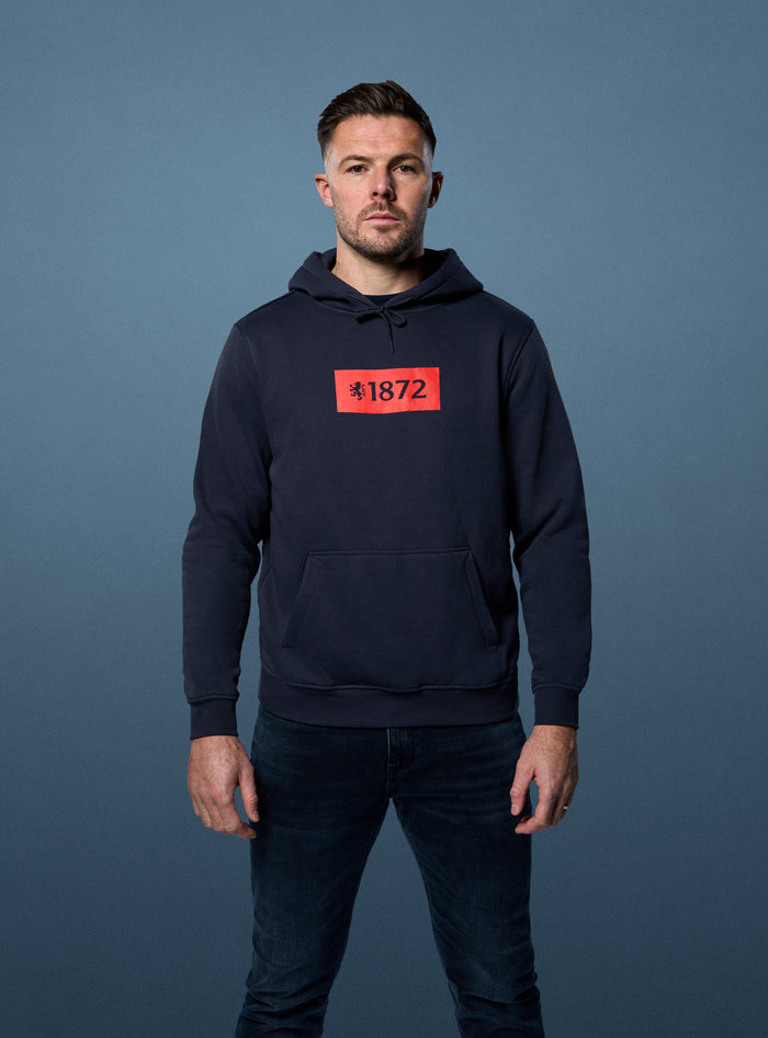 Unisex navy 25/26 Varsity 1872 Lion Hood shown on a model with a red 1872 logo on the chest