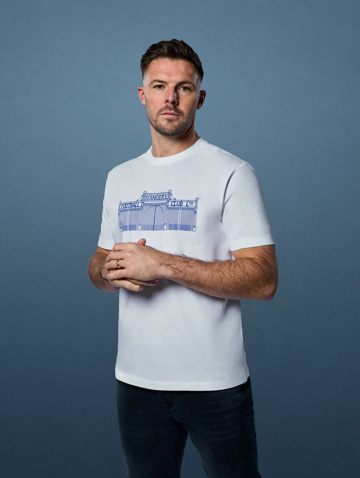 Male model wearing white Varsity Stadium Gate Tee with a blue gate graphic on the chest.