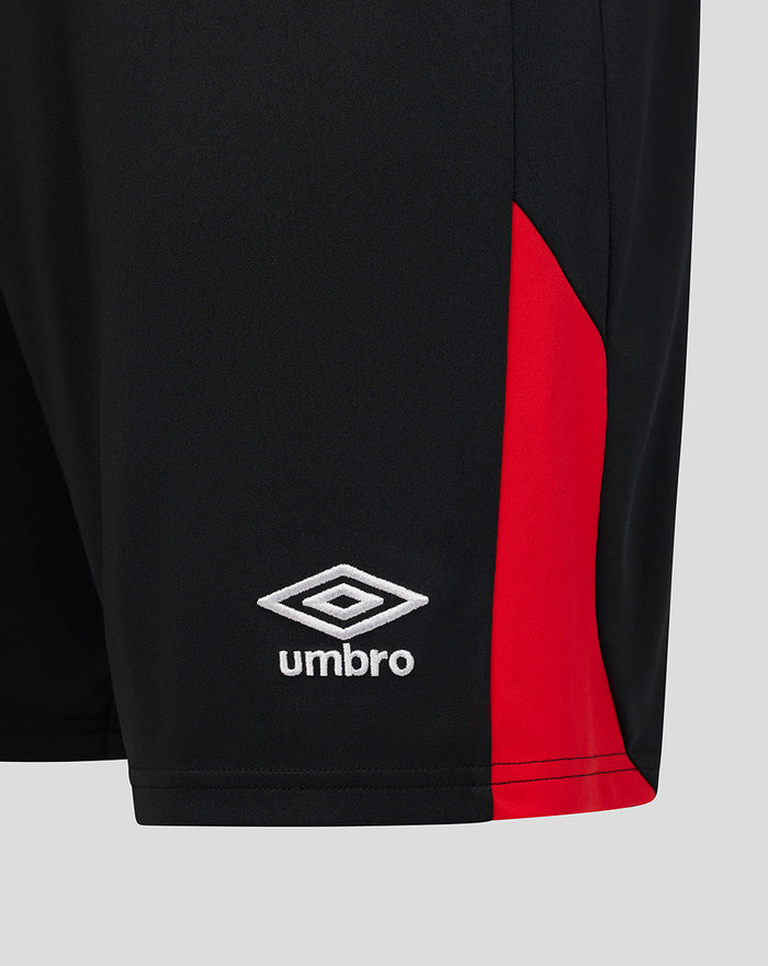 Close-up of the lower leg showing the white Umbro logo and red side panel on black shorts.