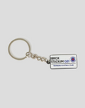 Street sign style keyring with a small white label attached to a metal chain.