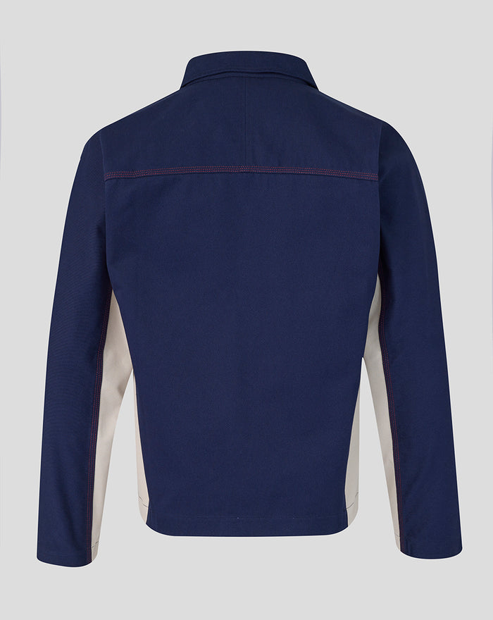 Back view of navy drill top showing red topstitching across the shoulders and beige side panels.