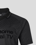 Close-up of a black unisex retro home blackout shirt with a dotted pattern, polo collar and an embroidered crest on the chest.