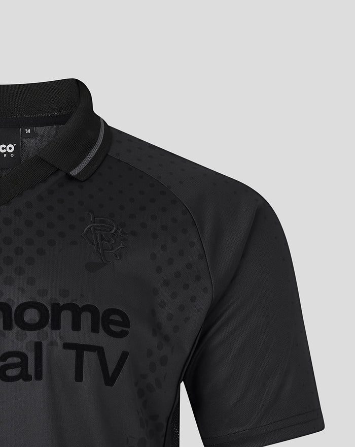 Close-up of a black unisex retro home blackout shirt with a dotted pattern, polo collar and an embroidered crest on the chest.