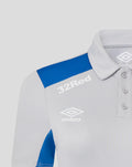 Front close up of a light gray poly polo with a blue shoulder panel and white Umbro branding including 32 Red on the chest