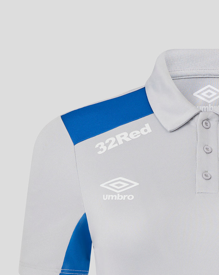 Front close up of a light gray poly polo with a blue shoulder panel and white Umbro branding including 32 Red on the chest