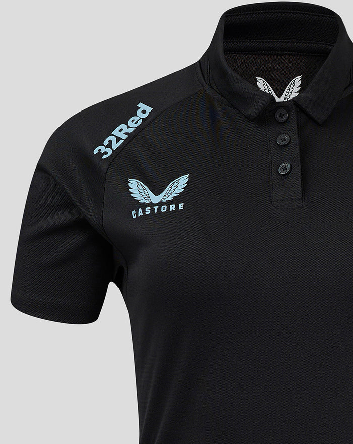Shoulder view of black polo featuring 32Red branding along the shoulder and a light blue Castore crest on the chest.