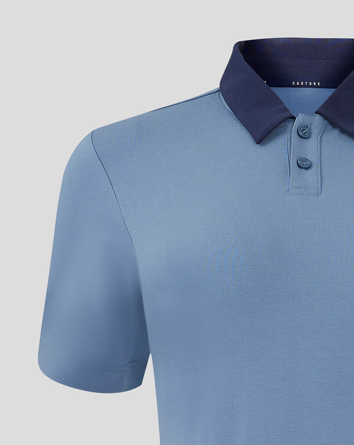 Close-up of light blue travel polo showing navy collar and Castore branding at the neck.