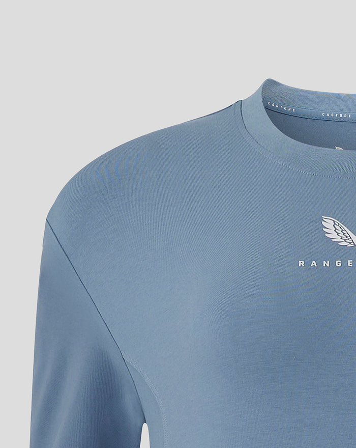 Light blue women's Rangers FC travel short sleeve T shirt close up showing ribbed crew neck and chest crest with Castore branding.