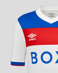 Partial view of Rangers junior away shirt with blue shoulder, red chest band, and white base featuring Umbro logo.
