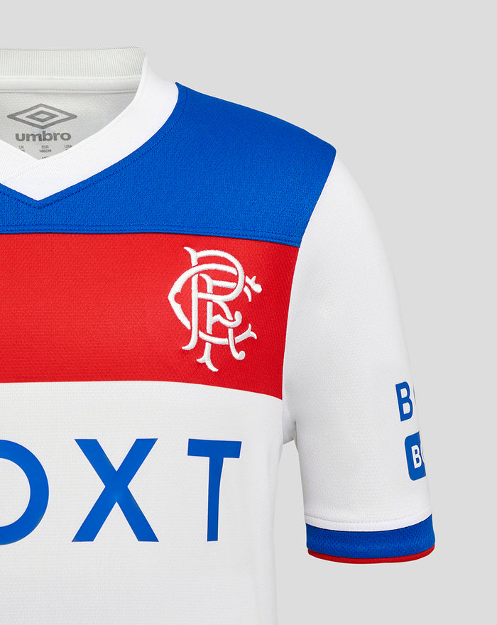 Close up of Rangers junior away shirt showing blue shoulder panel and red chest stripe with white crest on white fabric.