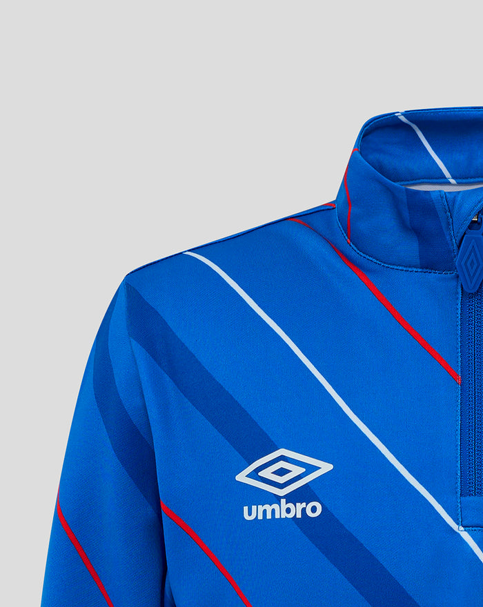 Shoulder close-up of blue junior home matchday quarter zip showing diagonal stripes and Umbro logo.