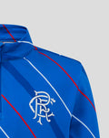 Close-up of blue junior home matchday quarter zip chest displaying club crest and Umbro logo with diagonal red and white stripes.