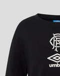 Close-up of black junior travel T shirt shoulder area showing large white crest and Umbro logo.