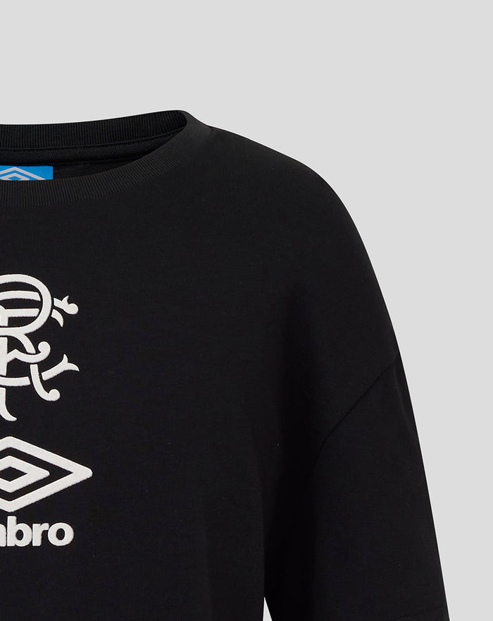 Close-up of black junior travel T shirt front with white club crest and Umbro logo.