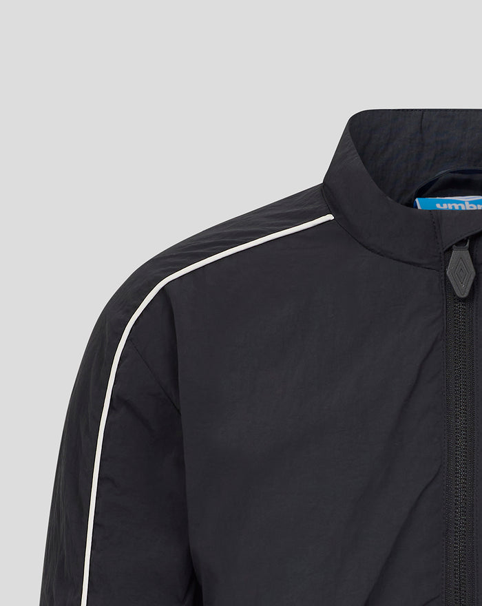 Shoulder close-up of navy Junior Travel Track Jacket with white piping along the seam and blue Umbro tag at the collar.