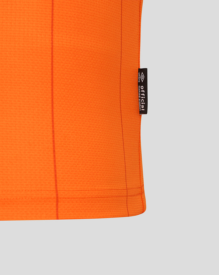 Close up of bright orange Rangers FC shirt fabric with a black side seam tag showing the Umbro label