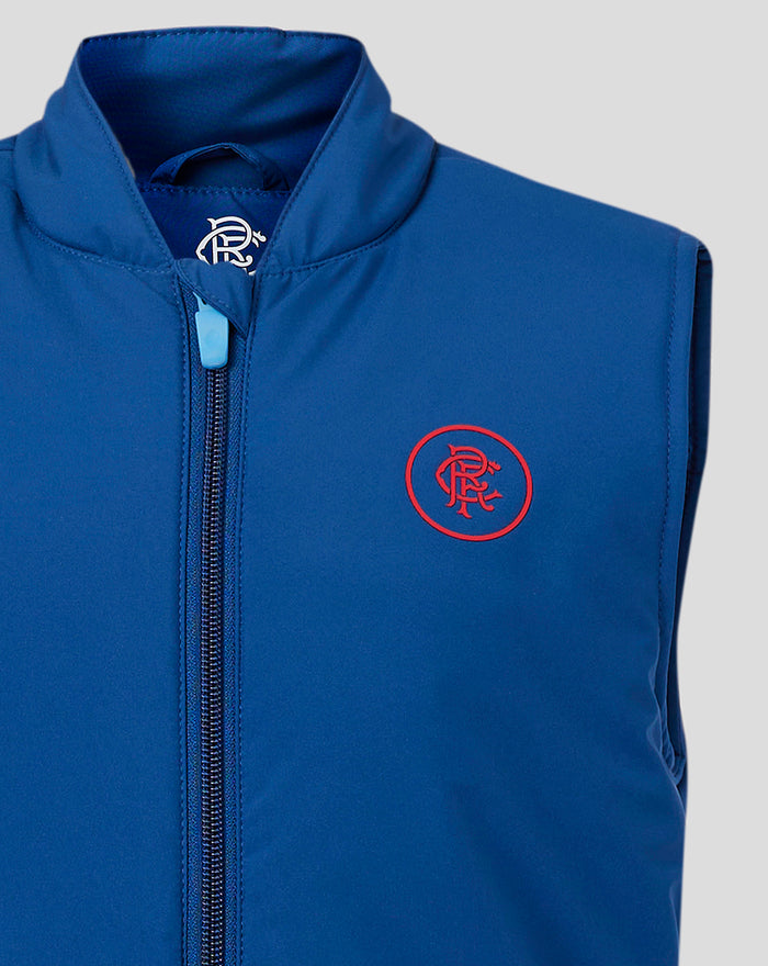 Close-up of navy junior gilet showing collar front zip with light blue pull and red crest on chest