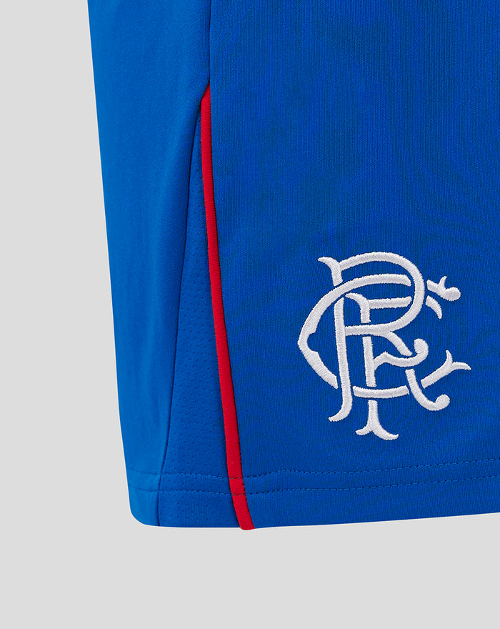 Close-up of blue shorts showing red side piping and white embroidered crest.