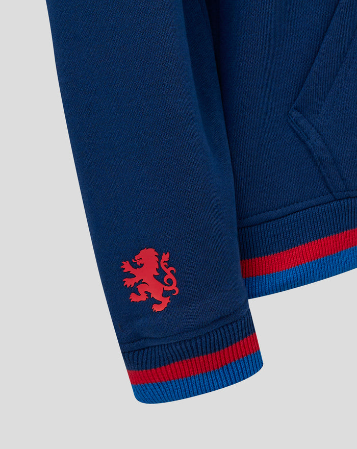 Close-up of navy knit hoodie fabric with a red lion crest near the hem and striped ribbed cuff.
