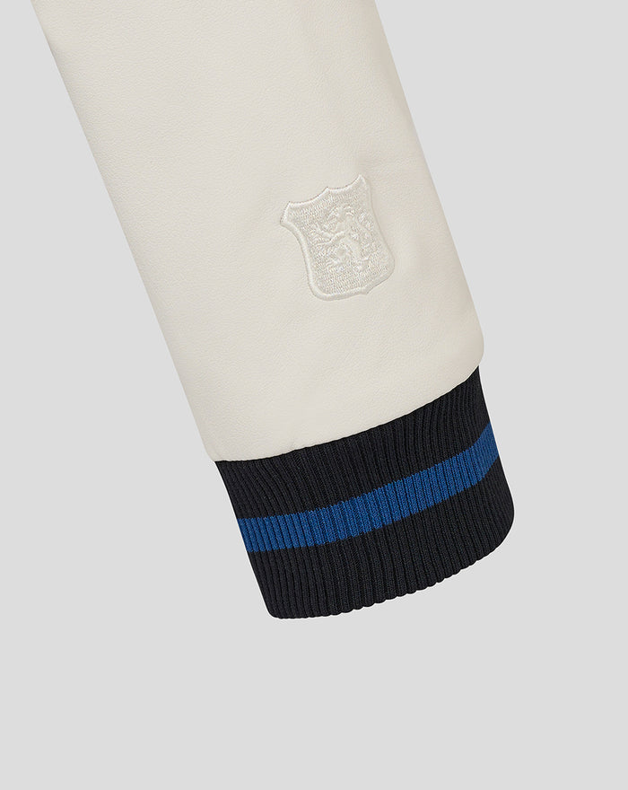 Cream sleeve with white shield patch and a navy striped ribbed cuff with blue stripe