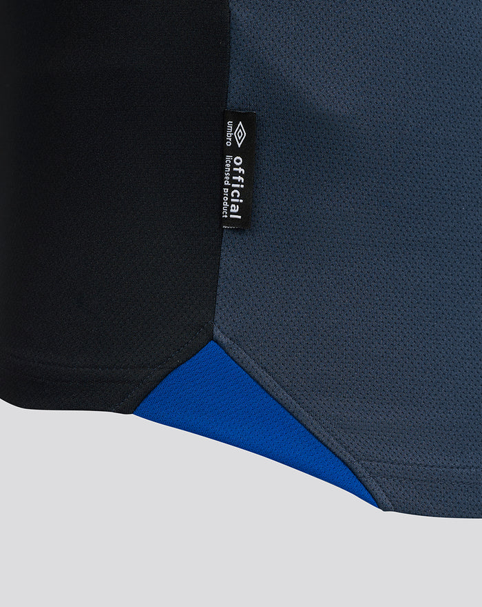 Close-up of the black side seam tag on the navy shirt showing official Umbro branding